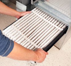 man_pulling_out_furnace_filter_from_furnace